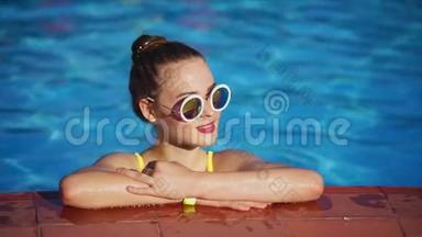 红头发的女人在游泳池里放松。 她站在游泳池旁边